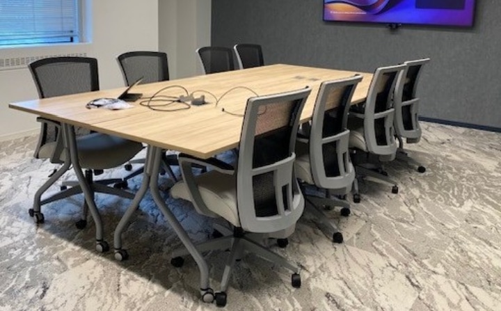 Modern tech-savvy conference room, with ergonomic seating, easy power access on the table and a large screen for presentations or virtual attendees.