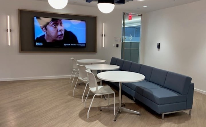 Comfortable breakroom seating with a blue couch and white tables and chairs. Designed to support collaboration and connection.