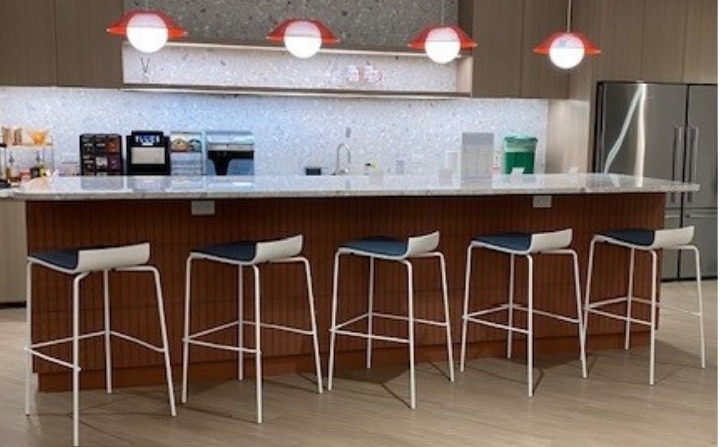 Office kitchen and coffee bar with quartz island and seating for coffee gatherings.